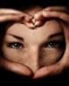 Two hands make a heart shape as face looks through them
